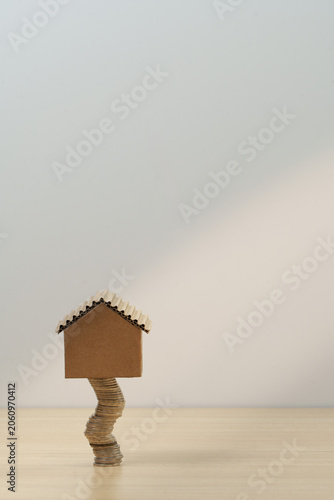 Real estate investment concept with cardboard house on stack of coins