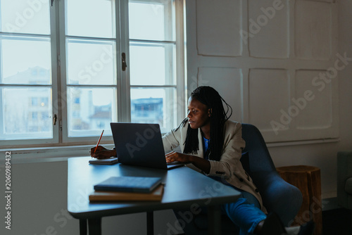 Young Black woman studying at desk with laptop