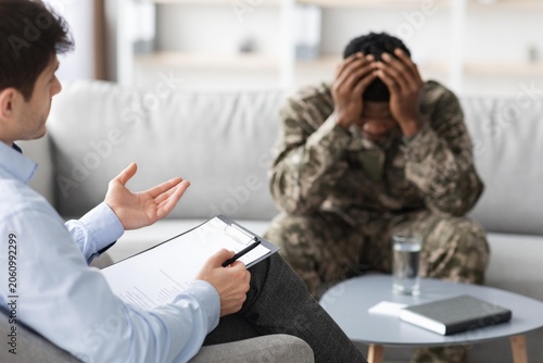 Obraz na płótnie Worried Black Male Soldier Experiencing Stress While Discussing Mental Health Issues With Therapist In Professional Office Setting, Seeking Support For Psychological Wellbeing, Healthcare Concept