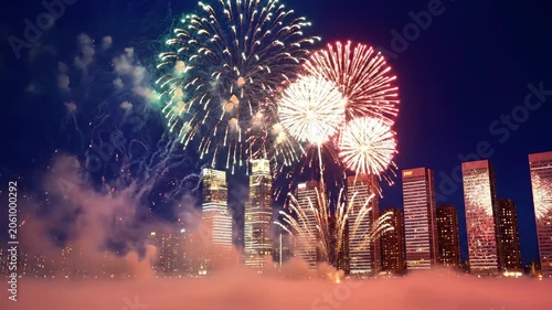 A vibrant cityscape at night with fireworks exploding in the sky