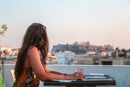 Woman at a restaurant enjoying the view of the Acropolis at sunset, Athens, Greece