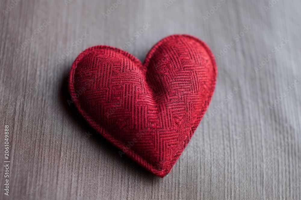Fototapeta premium Red fabric heart placed on a wooden surface representing love, care, and affection