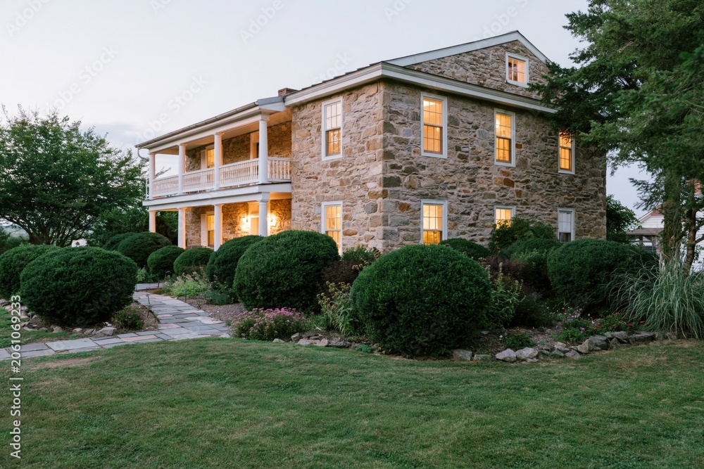 Fototapeta premium The Stone House with Rustic Courtyard and Warm Window Lighting at Dusk