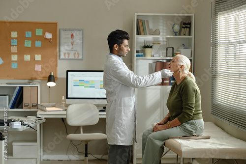 Senior woman visiting doctor, receiving neck examination in clinic during medical consultation. Healthcare checkup concept for senior care, diagnosis, insurance campaigns