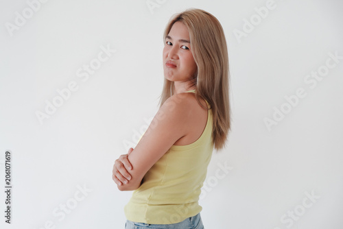 Konstfotografi Young Asian Thai woman with a skeptical, displeased expression, arms crossed, looking back over her shoulder