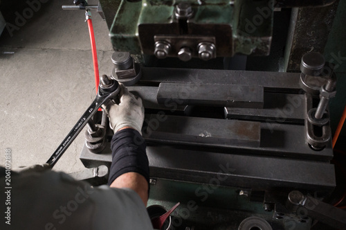 Fotografie Factory worker tightening a metal stamping die during press machine setup in a s