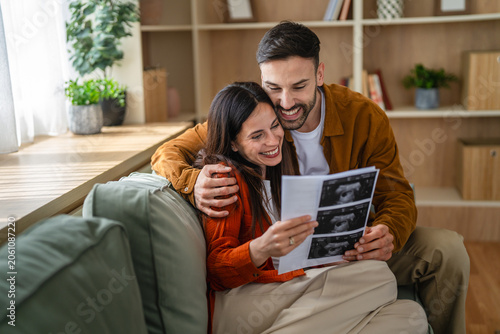 Bilde på lerret Happy couple looking at ultrasound images anticipating future parenthood