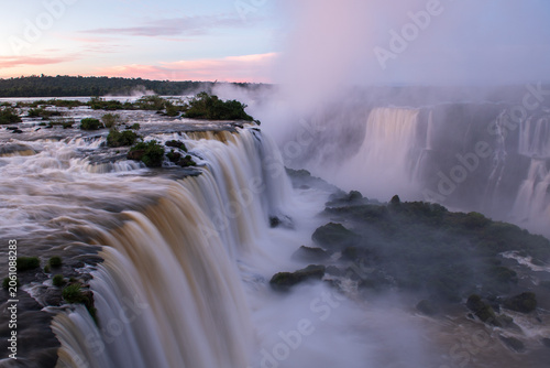 Obraz na plátně Dramatic breathtaking iguazu falls pouring water into river mist at sunset
