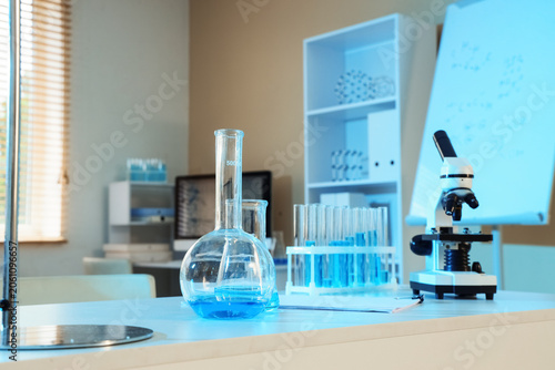 Scientific laboratory setup with glassware, blue liquid, test tubes, and micr...