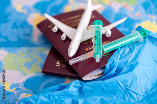 Passports, model airplane, and medical syringes on a world map background. Concept of medical tourism, vaccination requirements for international travel, and global health safety. Close-up of travel 