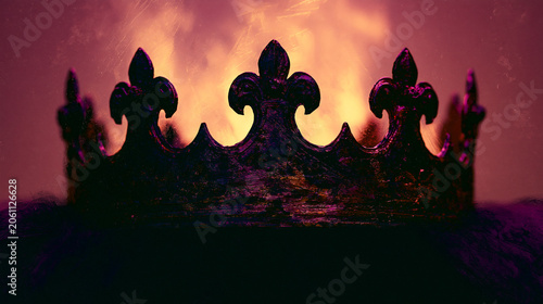 A dark, abstract medieval crown stands against a dramatic background of fractured light.
