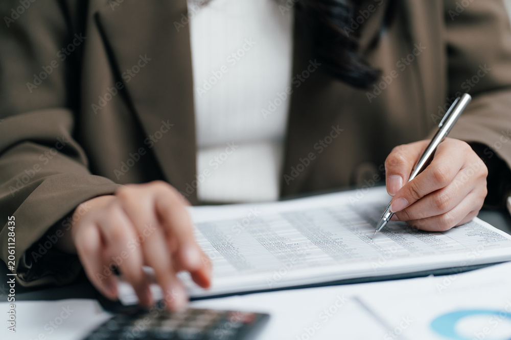 Naklejka premium Accountant using pen and calculator to review a financial data report on office desk, businesswoman auditing business tax, budget or investment profit