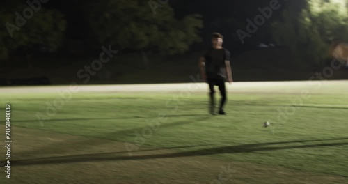 Diverse team bowling under lights chasing ball, wicketkeeper breaking bails to run out batsman