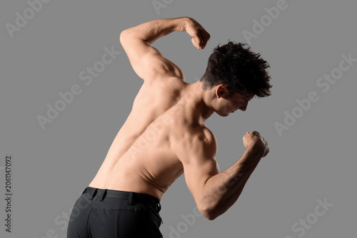 Muscular young man on grey ...