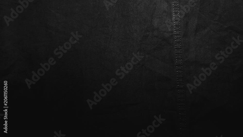 cinematic macro camera pans across textured black linen fabric with subtle double stitching revealing detailed weave