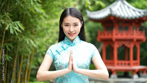 A woman in a cheongsam takes a photo in front of a pavilion and prays for blessings in the cheongsam garden