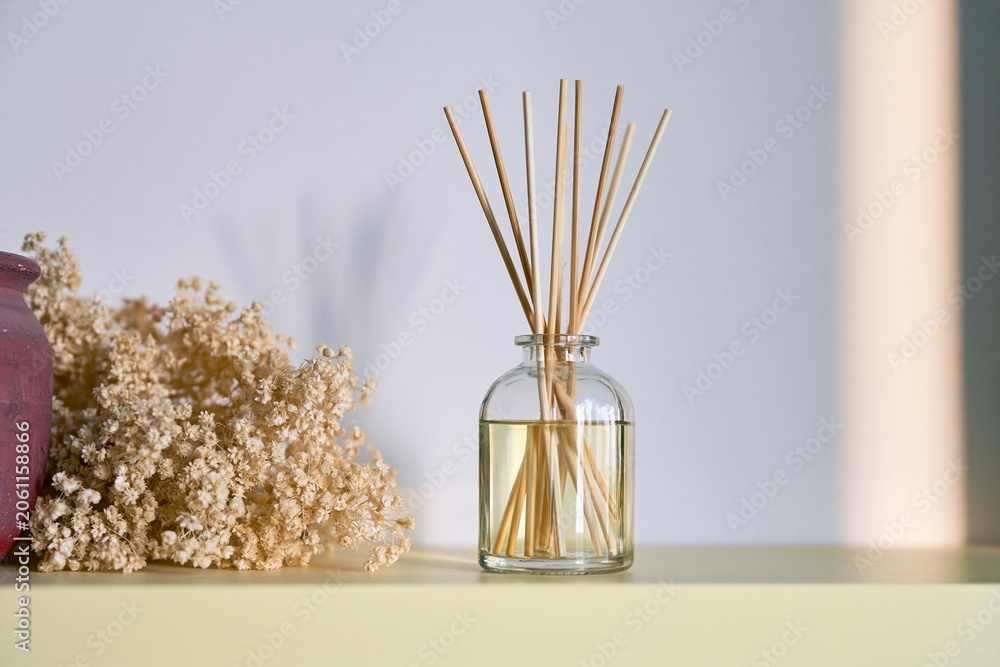 Fototapeta premium Glass reed diffuser with soft floral decor and sunlight