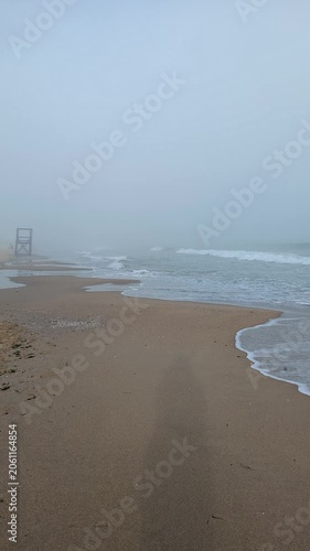 Misty coastal scene with waves rolling on sand  shore