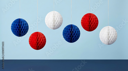 Red, white and blue honeycomb paper balls hanging against a blue background