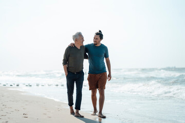 Father with arm around son walking at beach
