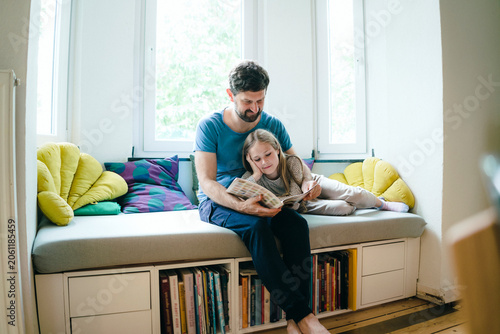 Father telling story to daughter at home