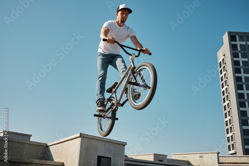Man jumping with BMX bike under sky on sunny day