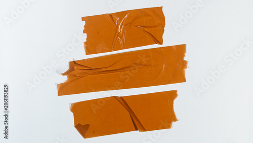 Obraz na płótnie Three strips of orange tape lie on a white surface