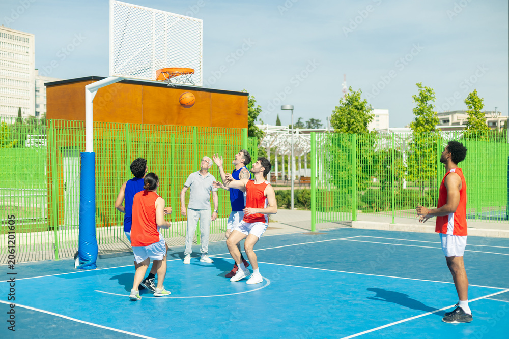 Fototapeta premium Diverse men playing active basketball game outdoors