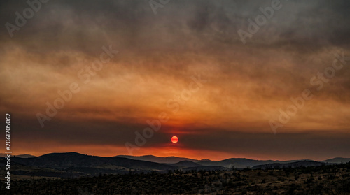 Wildfire smoke sunset blood orange disc rust amber smoky sky, climate ecology background