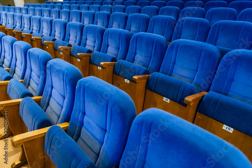Rows of empty blue seats in a cinema hall. Comfortable velvet chairs for viewers inside an auditorium. Interior of a theate