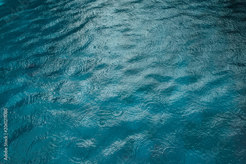 Dark blue swimming pool water shows flowing ripples and light reflections across the surface. Suitable for aquatic backgrounds, pool water texture