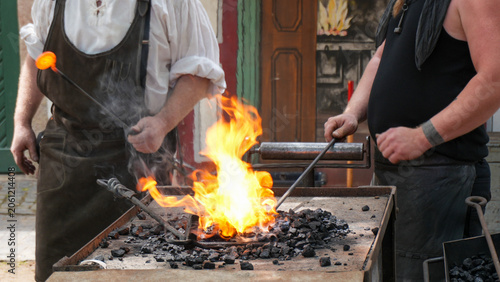 Bilde på lerret two blacksmiths forging hot glowing metal in a bright fire at a traditional medi