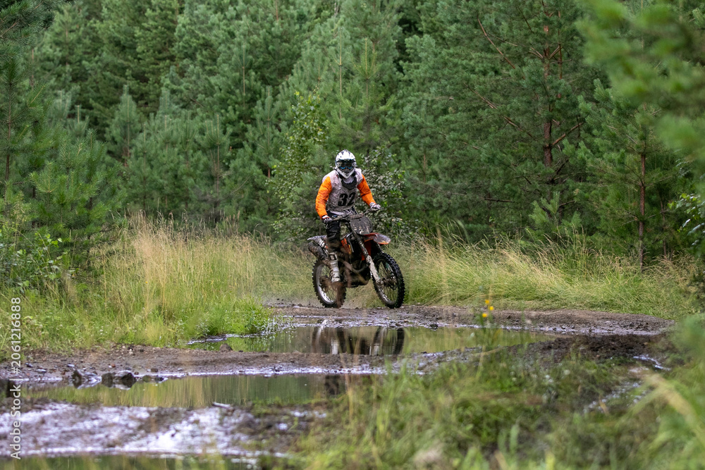 Naklejka premium Enduro racer in front of puddle of water during competition race