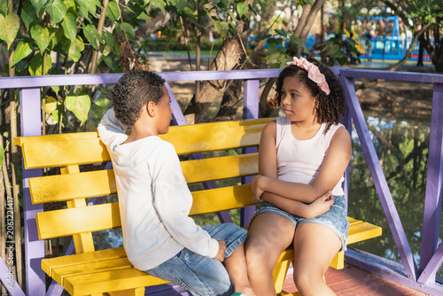 Kids performing conversation sitting on park bench
