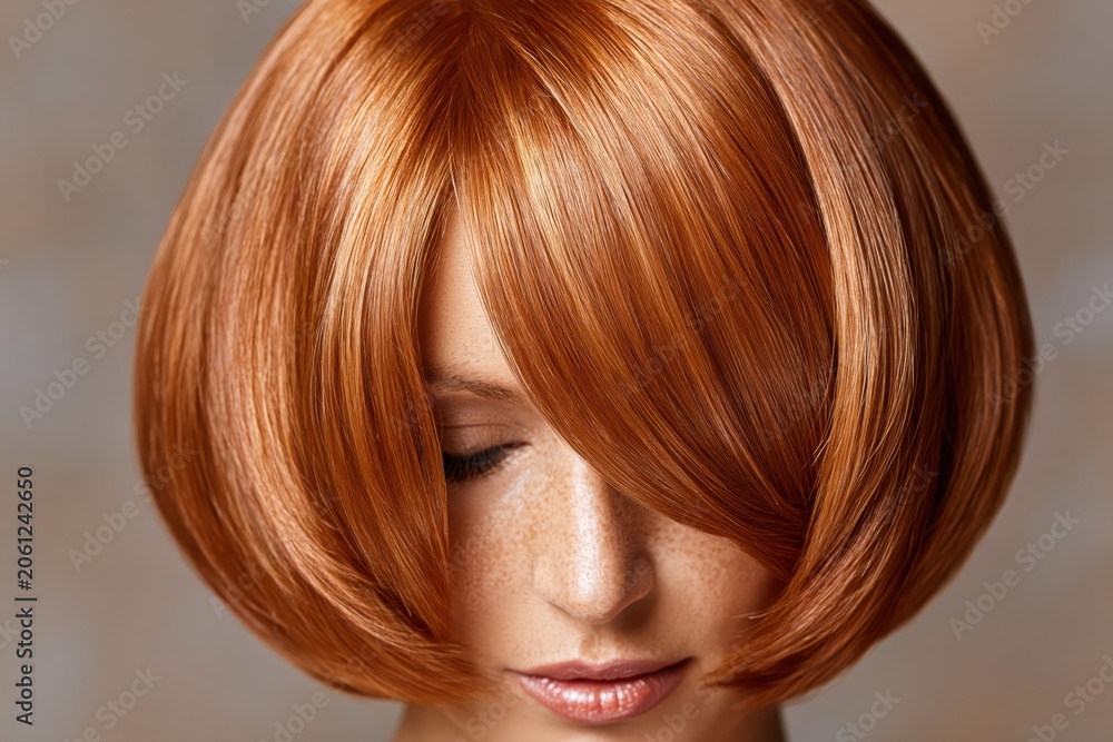 Naklejka premium Close-up portrait of a woman with vibrant auburn bob haircut and natural freckles, looking down.