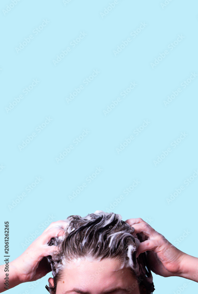 Naklejka premium Woman Washing her hair with shampoo foam isolated on blue background. Symbol of hair care. Treatment and health related theme.
