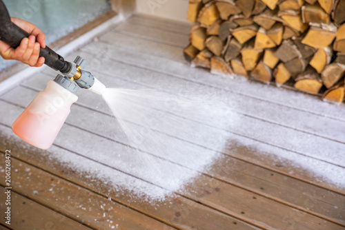 Hand applying soap foam canon on wooden deck with high pressure washer. Concept: professional cleaning service