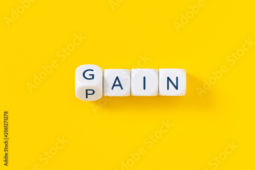 Foto flipping block changing gain or pain word on yellow background