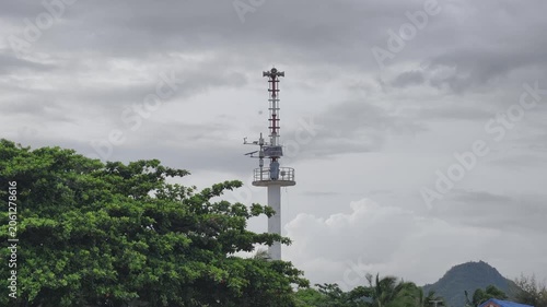 A tall communication tower rises above treetops