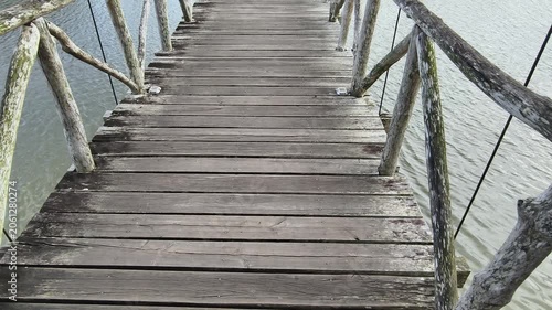 A wooden boardwalk bridge curving across a lake