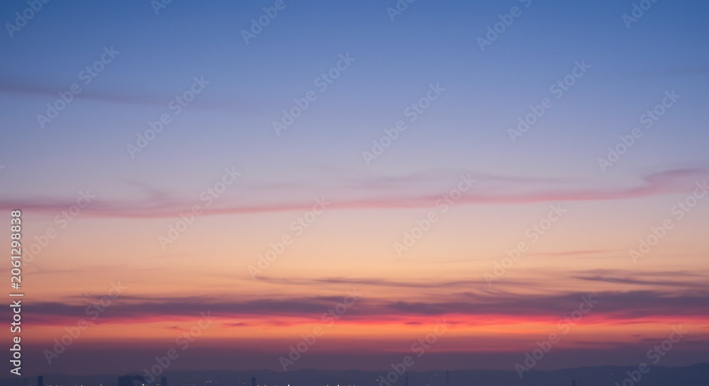 Fototapeta premium Vivid twilight sky capturing a serene moment as colors gently shift from soft blue to warm orange and fiery red. AI Generated