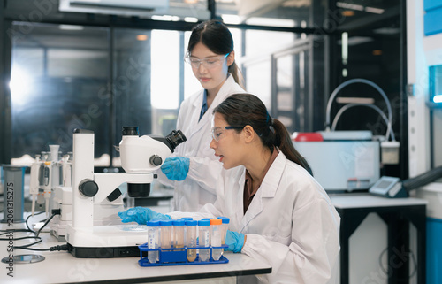 Photos Two Asian female environmental scientists analyzing water quality samples with centrifuge and petri dish in laboratory
