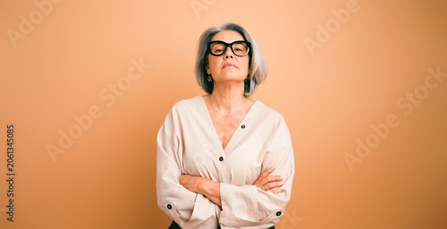 Obraz na plátne Senior woman wearing glasses and casual clothing, confidently posing with arms c