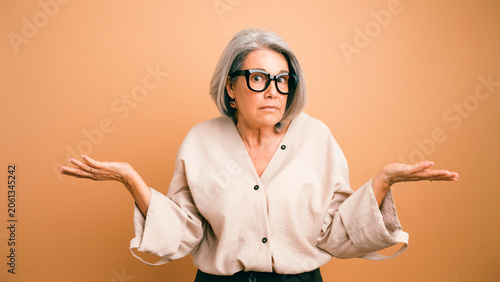 Obraz na płótnie Senior woman shrugging, having a confused and uncertain expression, standing aga