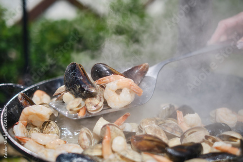 Cooking paella with seafood in a frying pan.  Hot Vibrant Spanish Paella. Selective focus. 