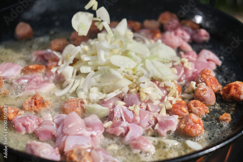 Cooking paella with chicken, onion, seafood, and vegetables in a frying pan. Hot Vibrant Spanish Paella. Selective focus. 