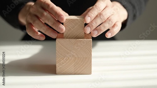 Hands stacking wooden blocks, representing growth, development, business strategy, problem solving, teamwork, and planning