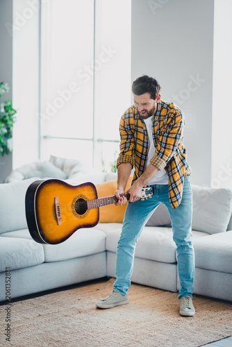 Картината върху платно Frustrated man swinging acoustic guitar in living room, shouting and pretending