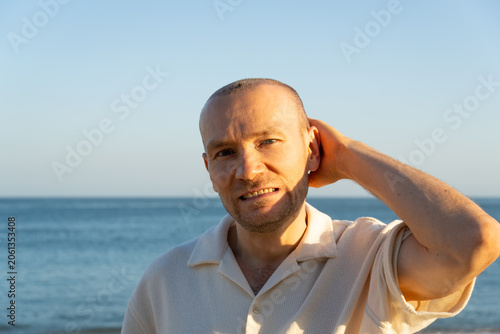 Fotografie A portrait of a middle-aged man after a hair transplant procedure, looking hesit