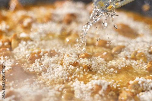  Hot Vibrant Spanish Paella. Cooking paella with chicken, seafood, and vegetables in a frying pan. Selective focus.